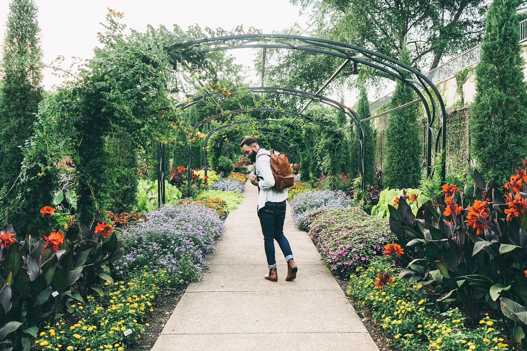 Gepflegter Gartenweg mit bunten Blumenbeeten und Rankbögen